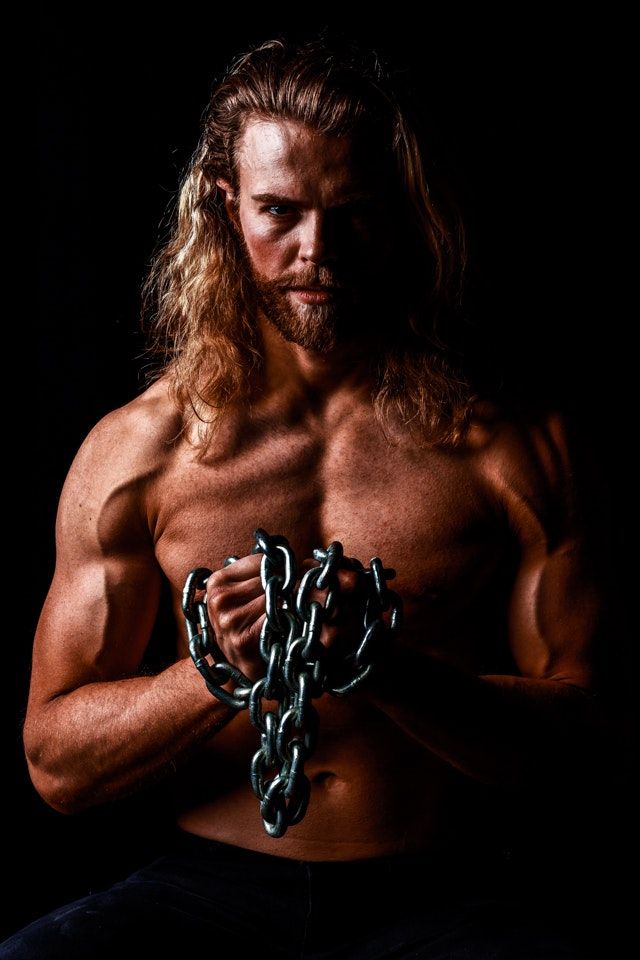 Dramatic fitness portraits with chains showing muscular physique against dark background.