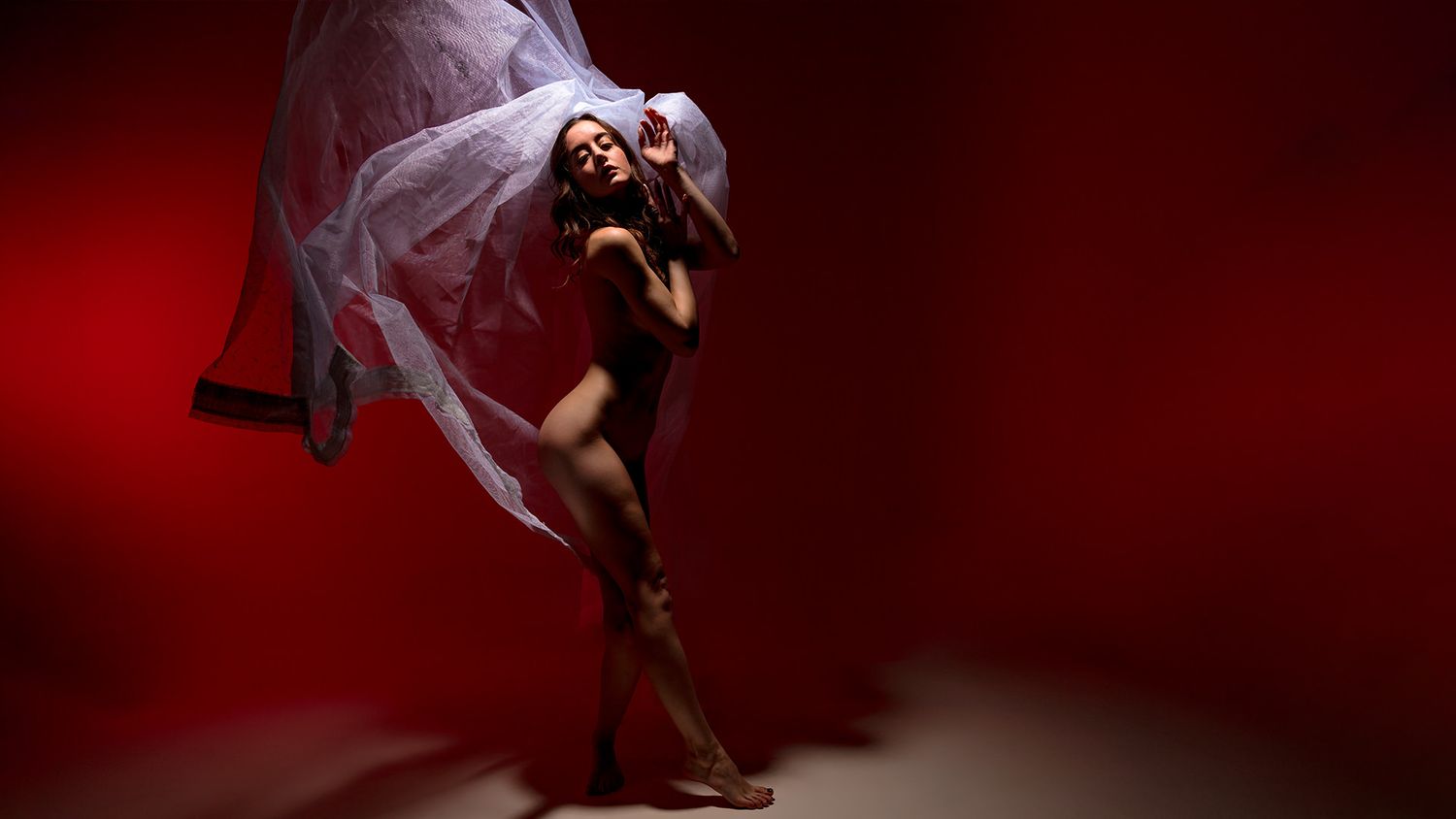 Dramatic dance performance with red lighting and flowing movement captured in silhouette.