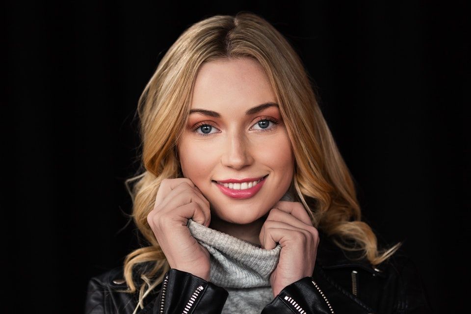 Fashion portrait series with cozy winter sweater and natural makeup against dark backdrop.