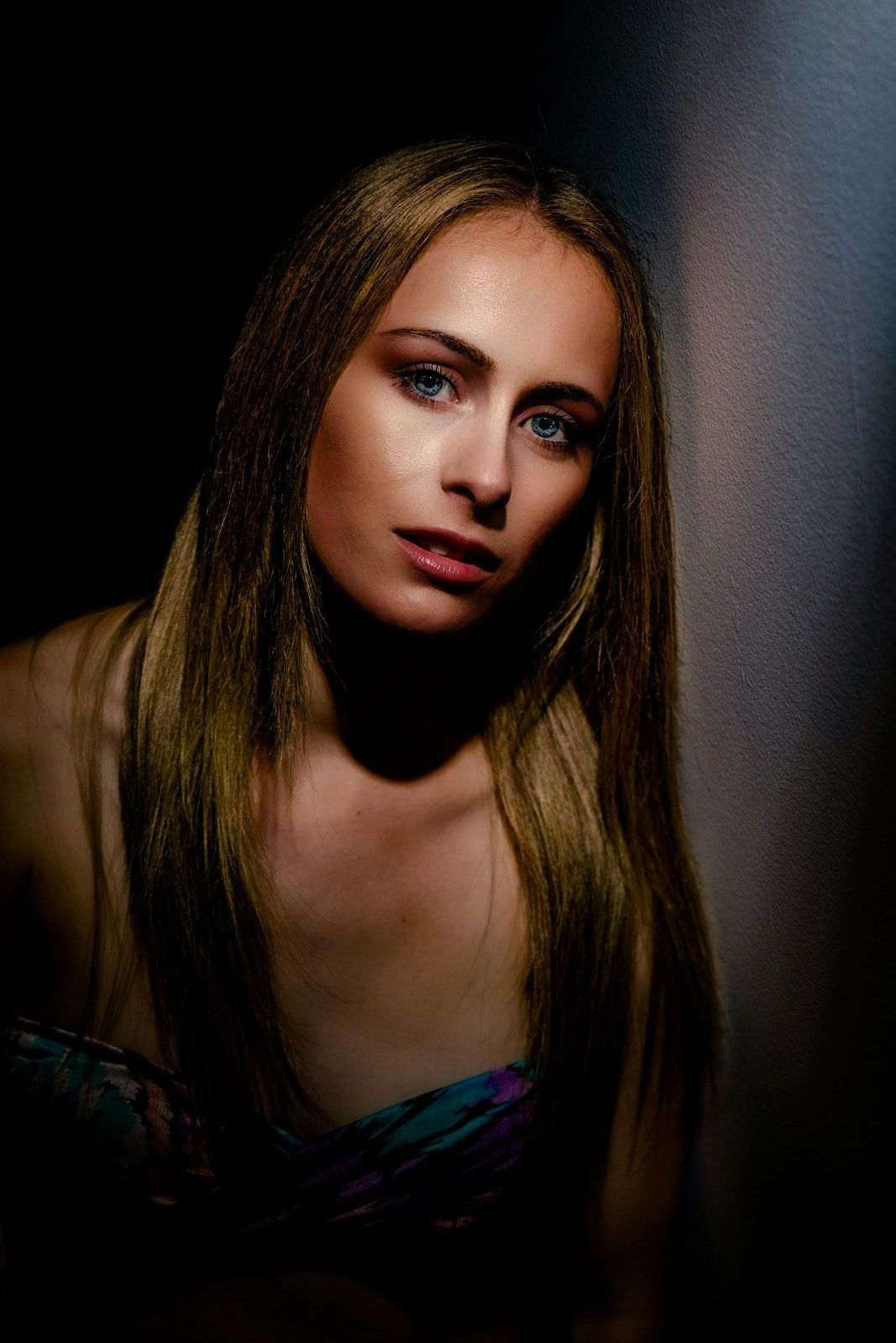 Dramatic portrait series with moody lighting showing long dark hair and red lipstick against black background.