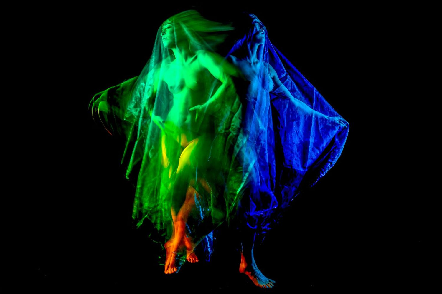 Colorful glowing light trails in green, blue and orange create abstract patterns against a black background.