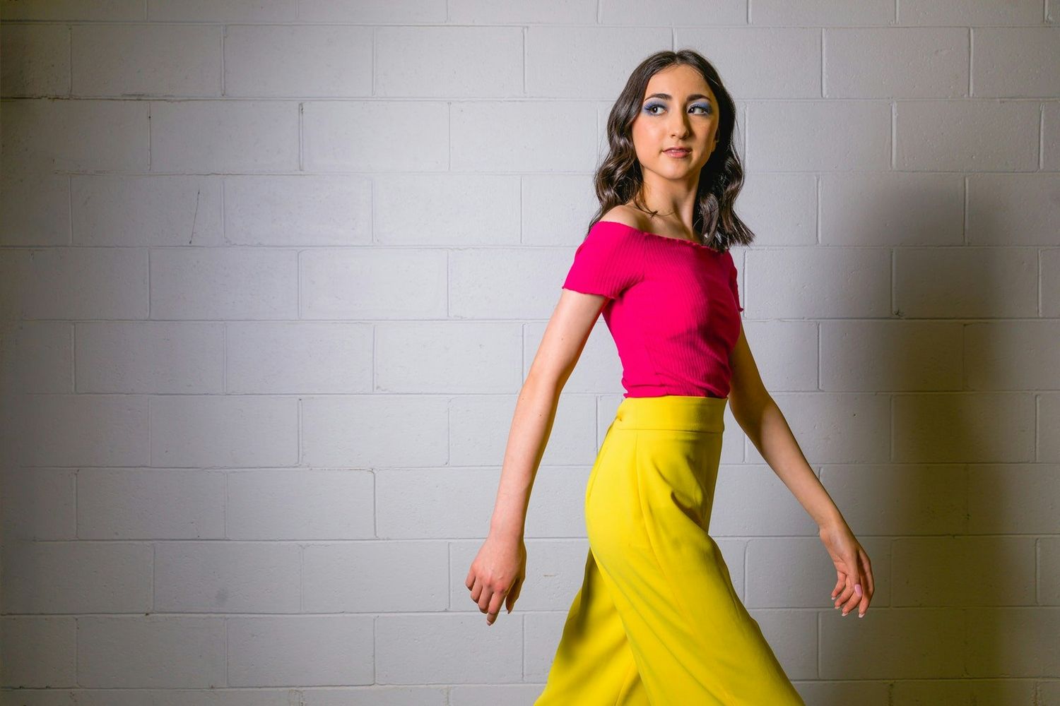 Dynamic fashion poses in colorful dresses against white studio wall.