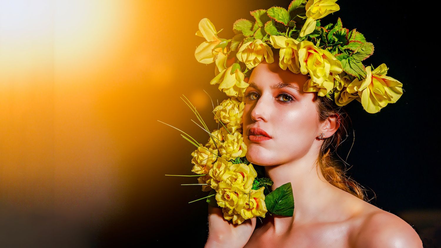 Creative portraits with yellow flower crown against dark background.