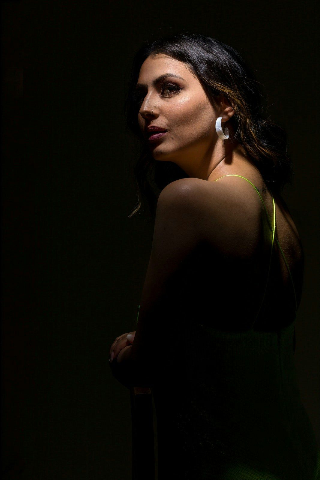 Dramatic side profile portraits with moody lighting and statement earrings.