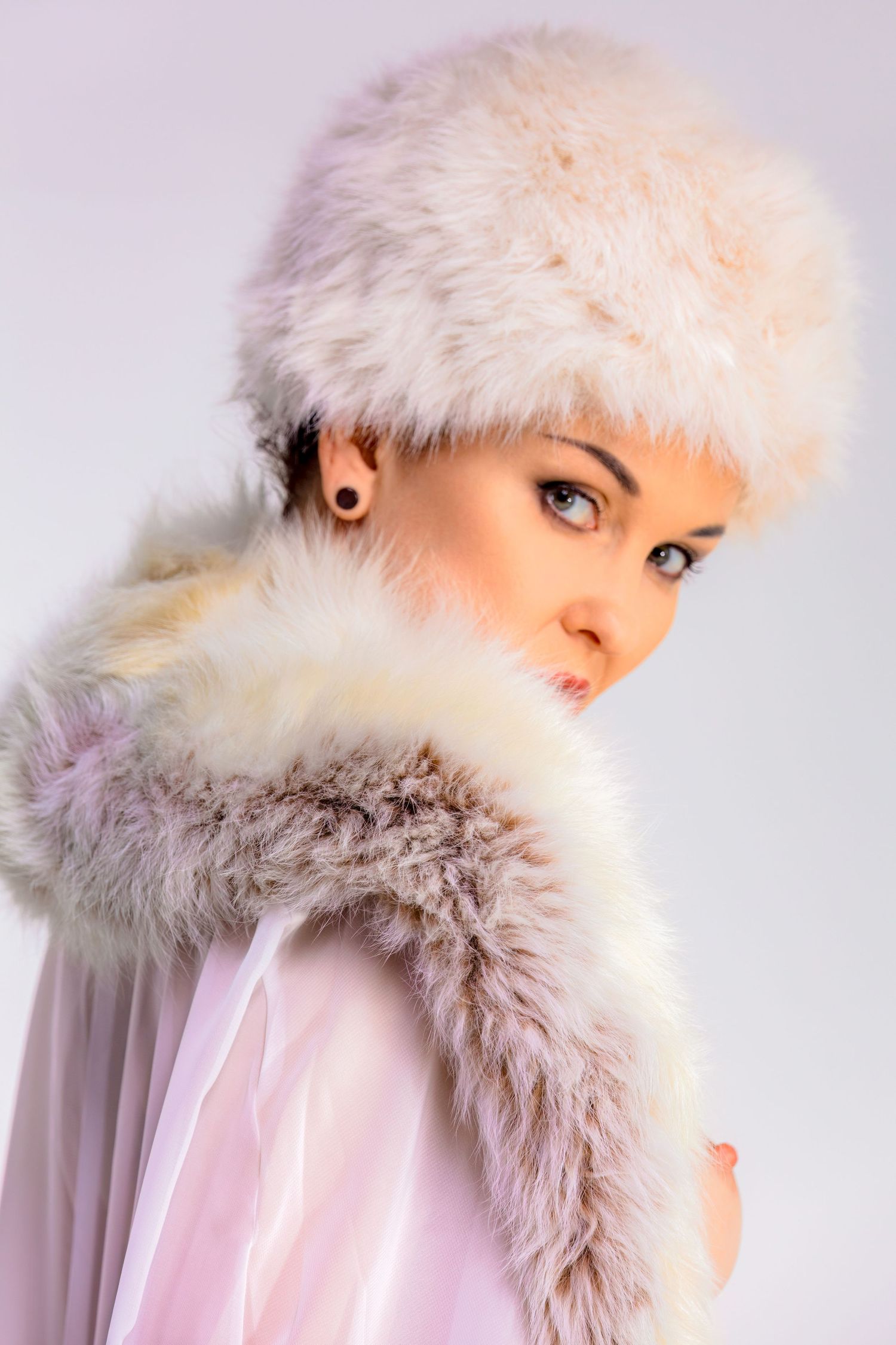 Winter fashion portrait featuring soft fur hat and delicate styling.