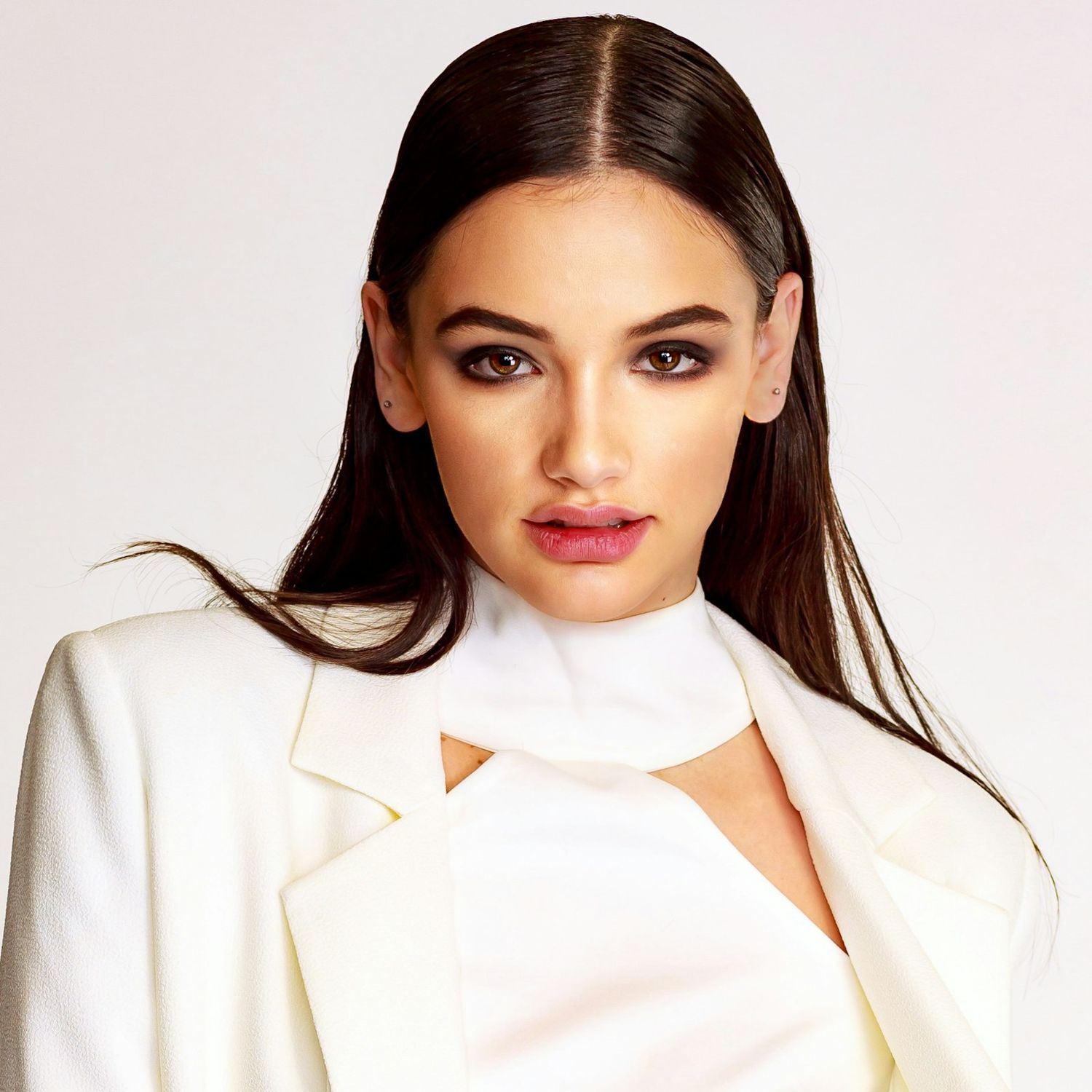 Clean studio portraits in white blazer against light background.