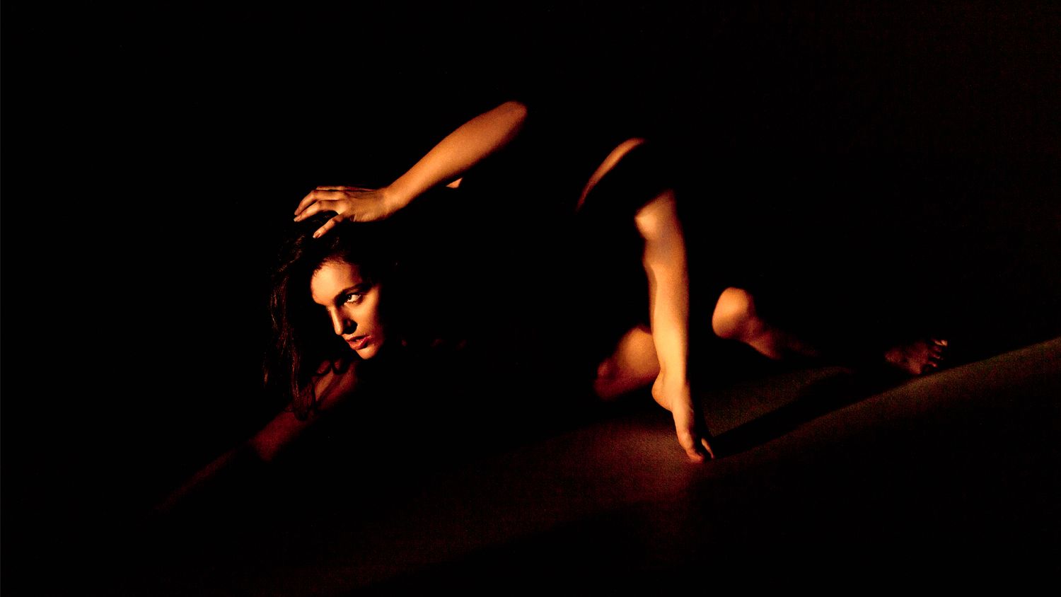 A silhouetted figure performs an acrobatic dance move in dramatic red stage lighting.