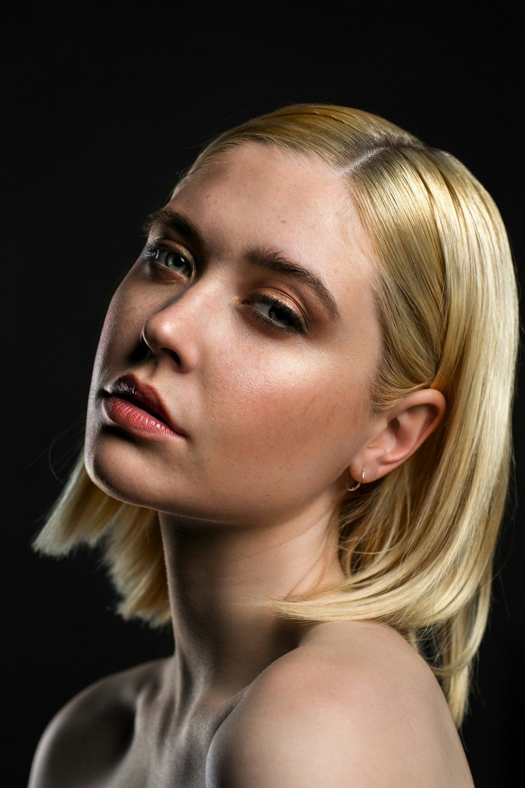 Artistic beauty portraits featuring blonde bob hairstyle and red lips against black backdrop.