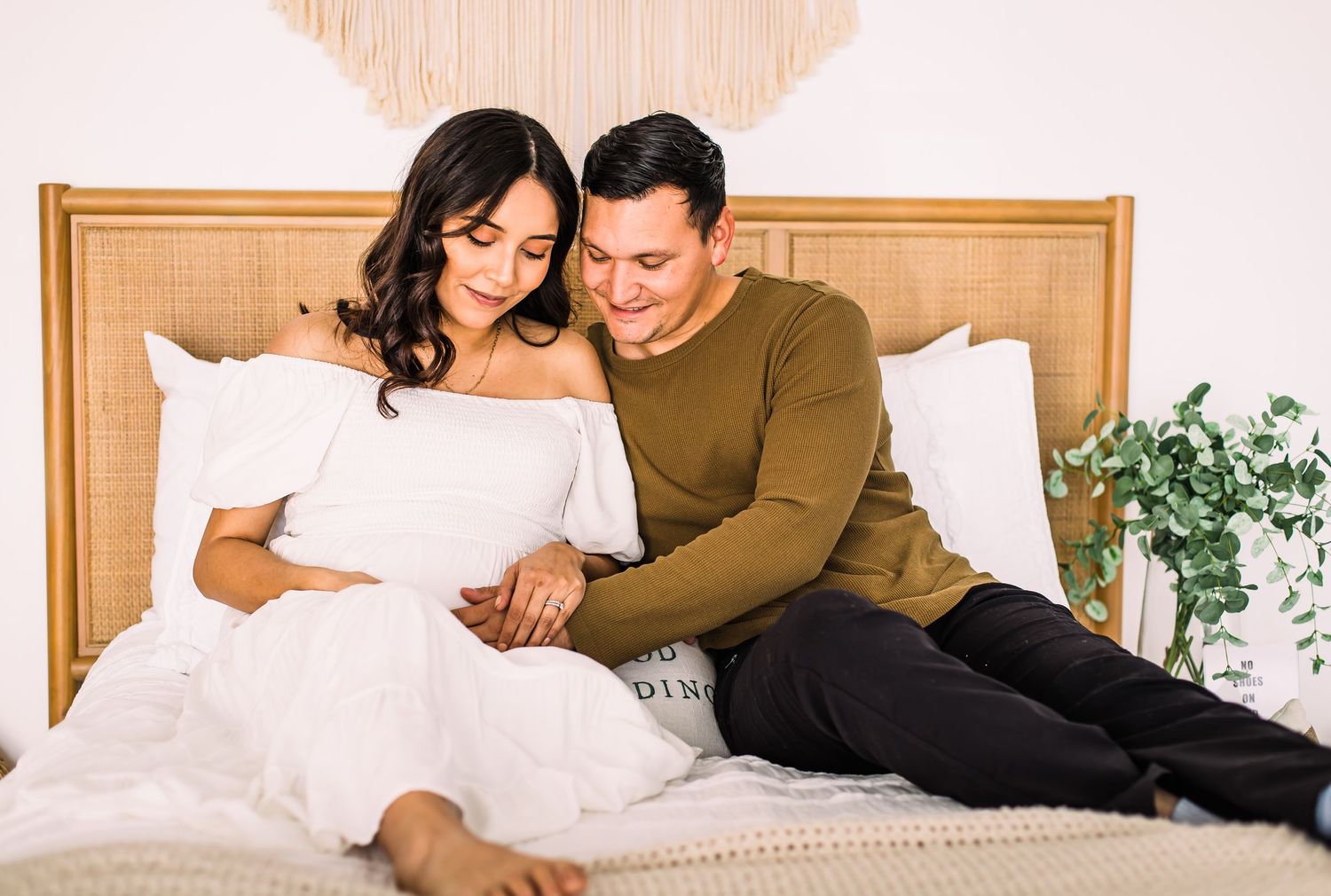 couple looking down at pregnant belly on bed