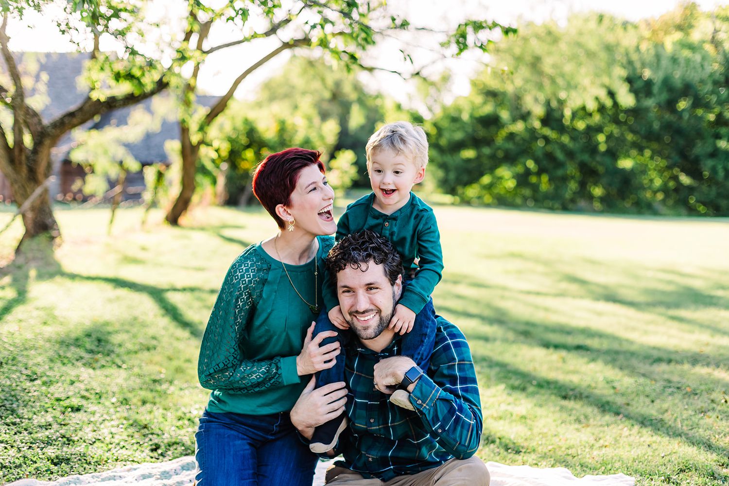 Family members share joyful moments together on a sunny grassy hillside.