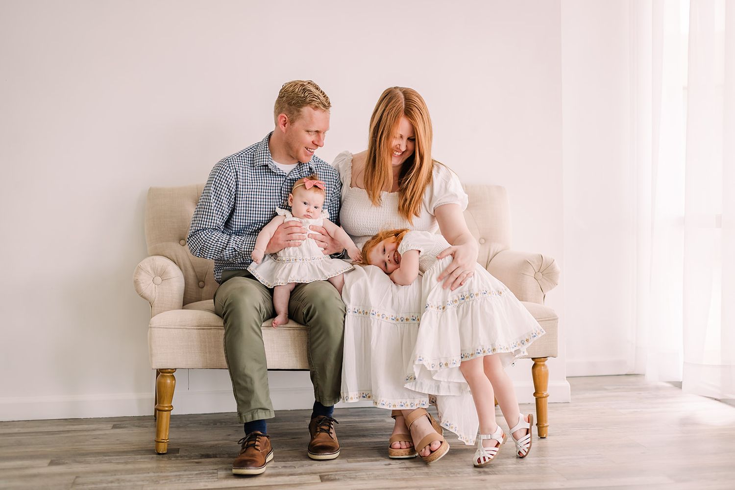 Family portrait session in white room showing candid moments and connections.