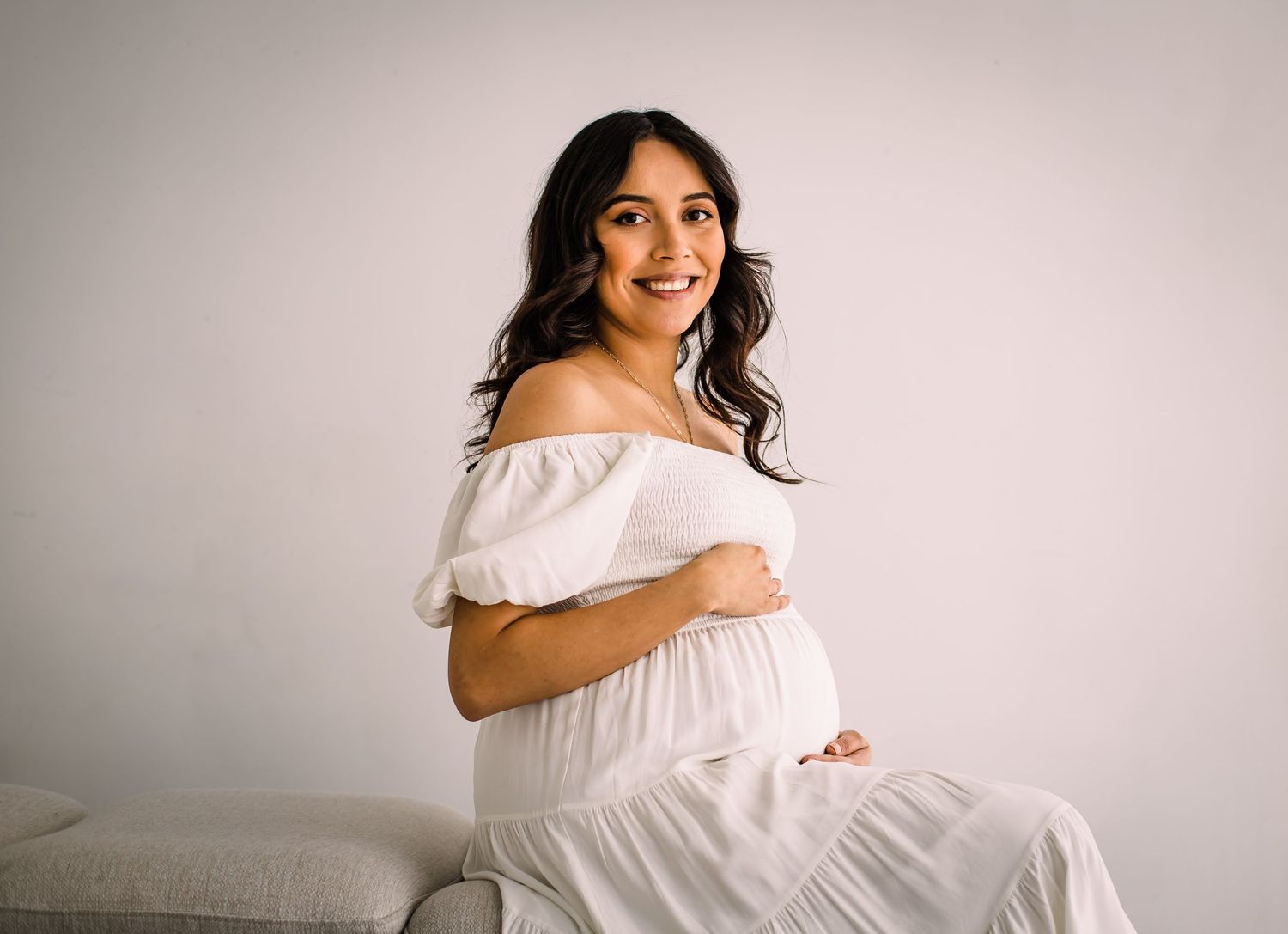 studio maternity photoshoot mom in white flowy dress smiling