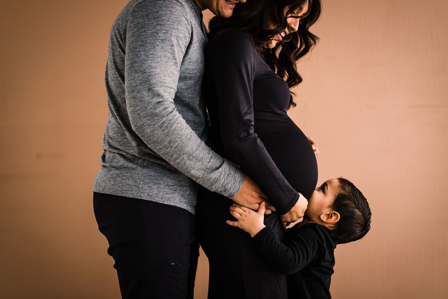 family maternity session child kissing moms belly