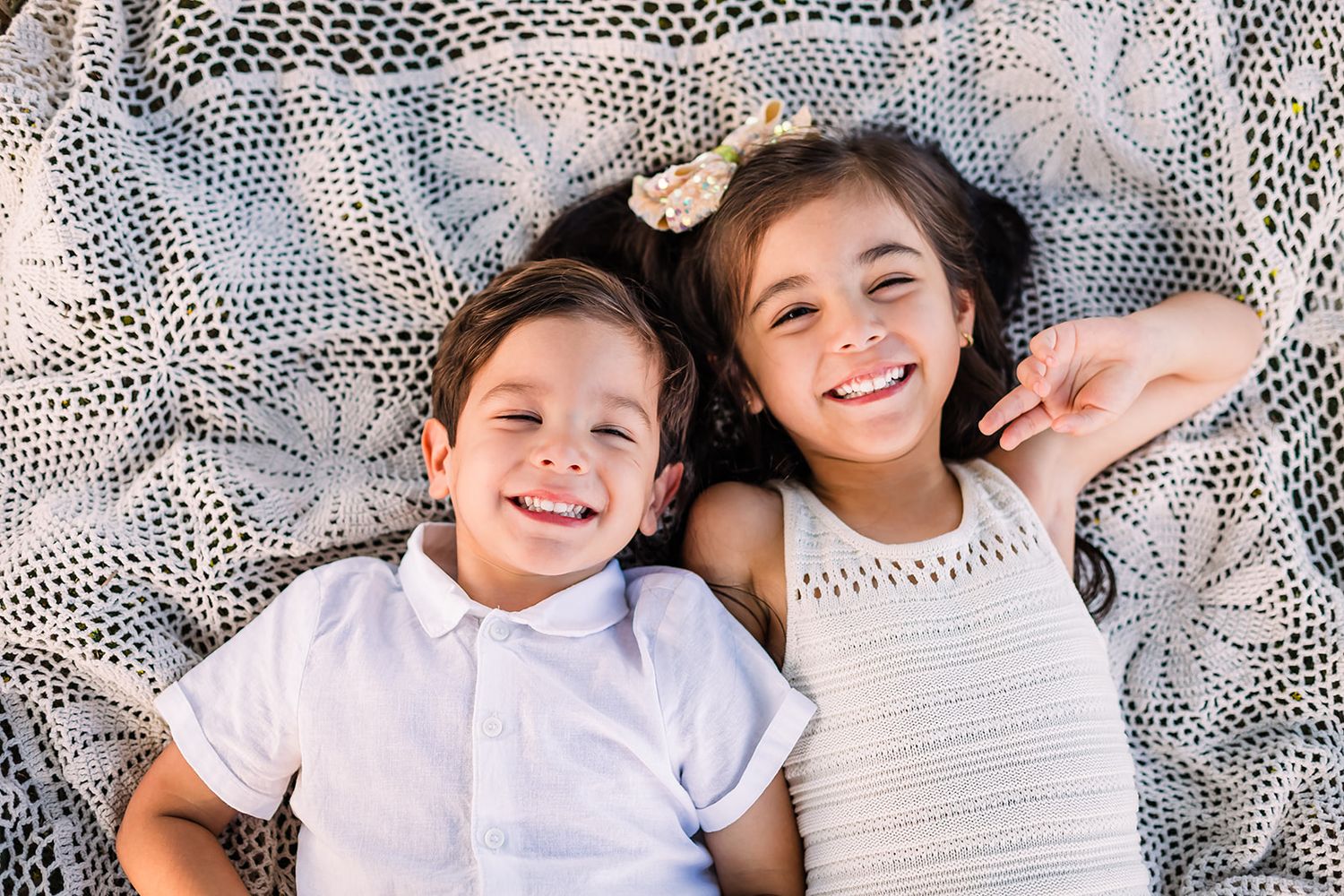 Family portrait session with white lace backdrop showing joyful expressions.