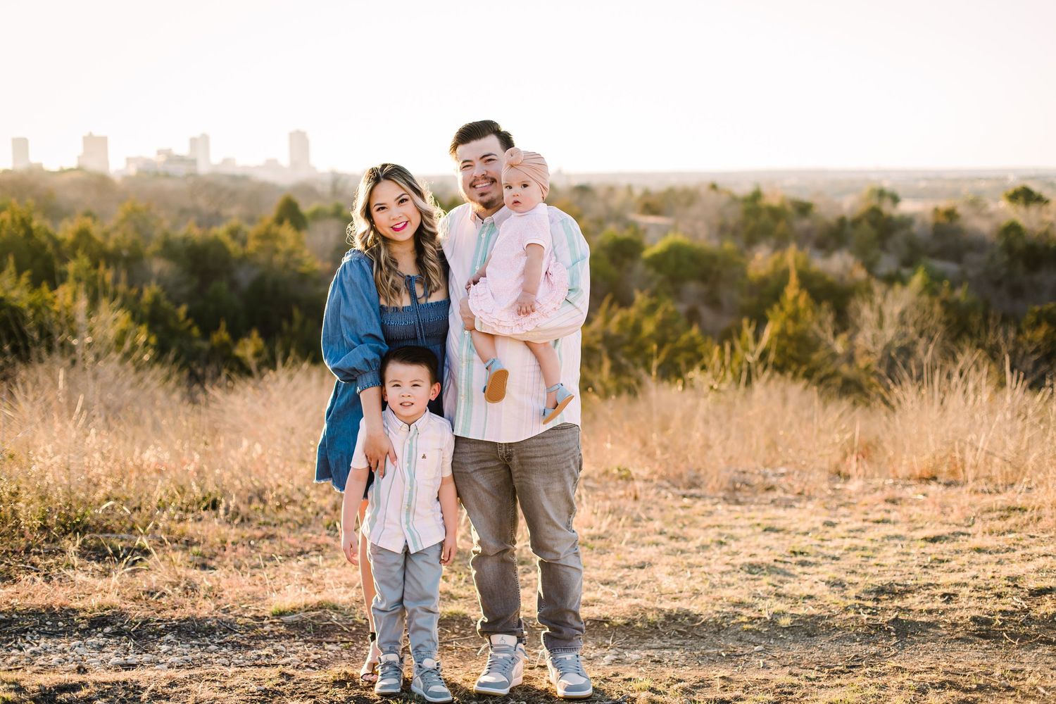 Family photoshoot in a golden field during sunset with mountains in background.