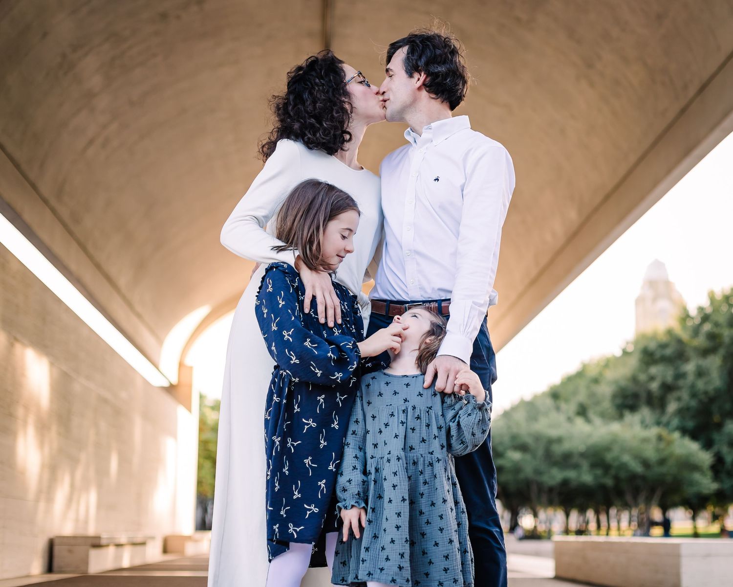 Family photo session under concrete bridge structure with natural poses and interactions.
