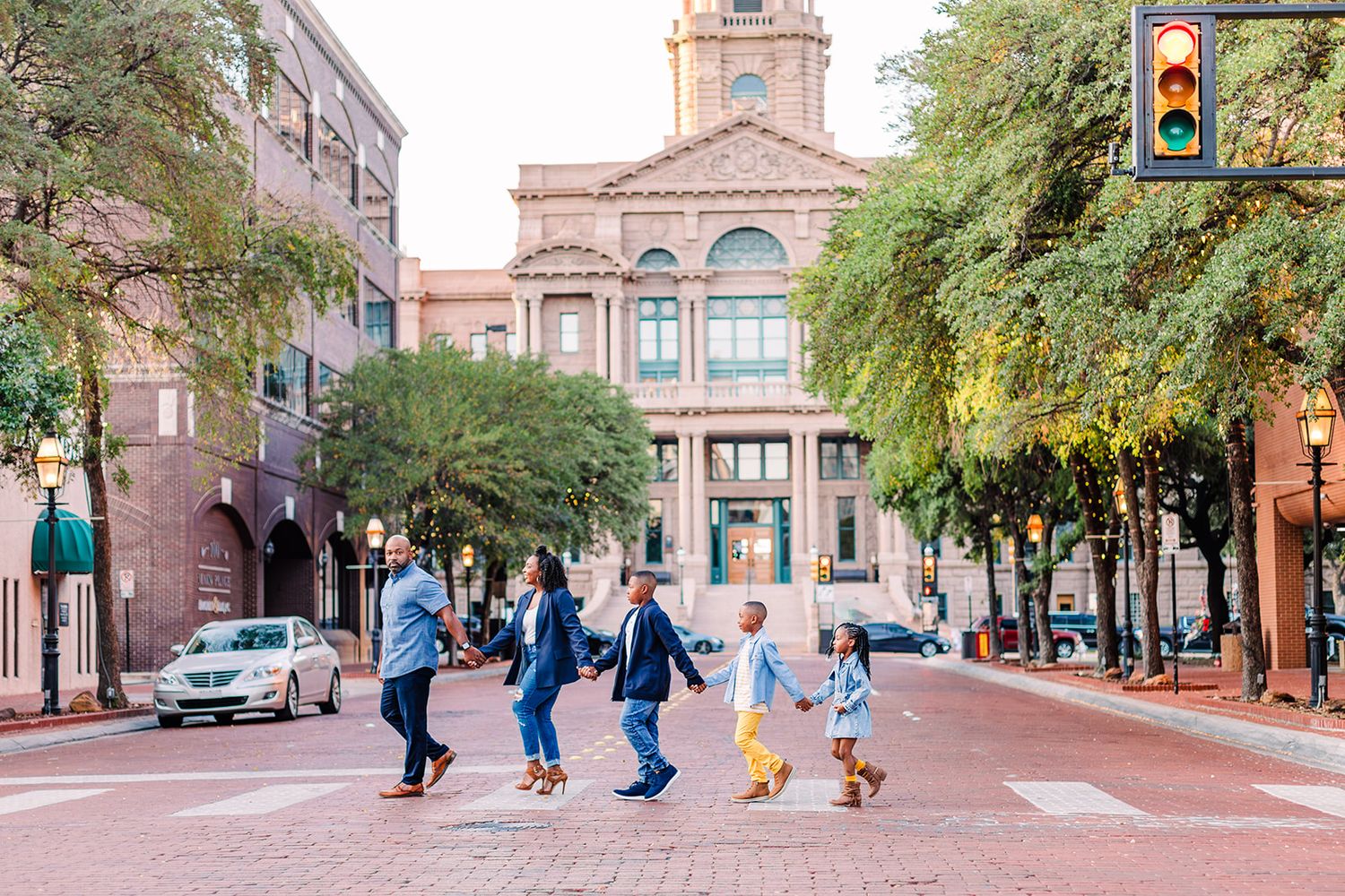 Students walk across the tree-lined brick plaza in front of a historic university building with classical architecture.