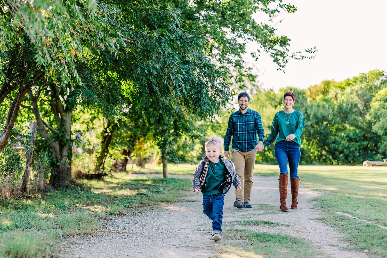 A group walks together along a tree-lined path during golden hour in a park setting.