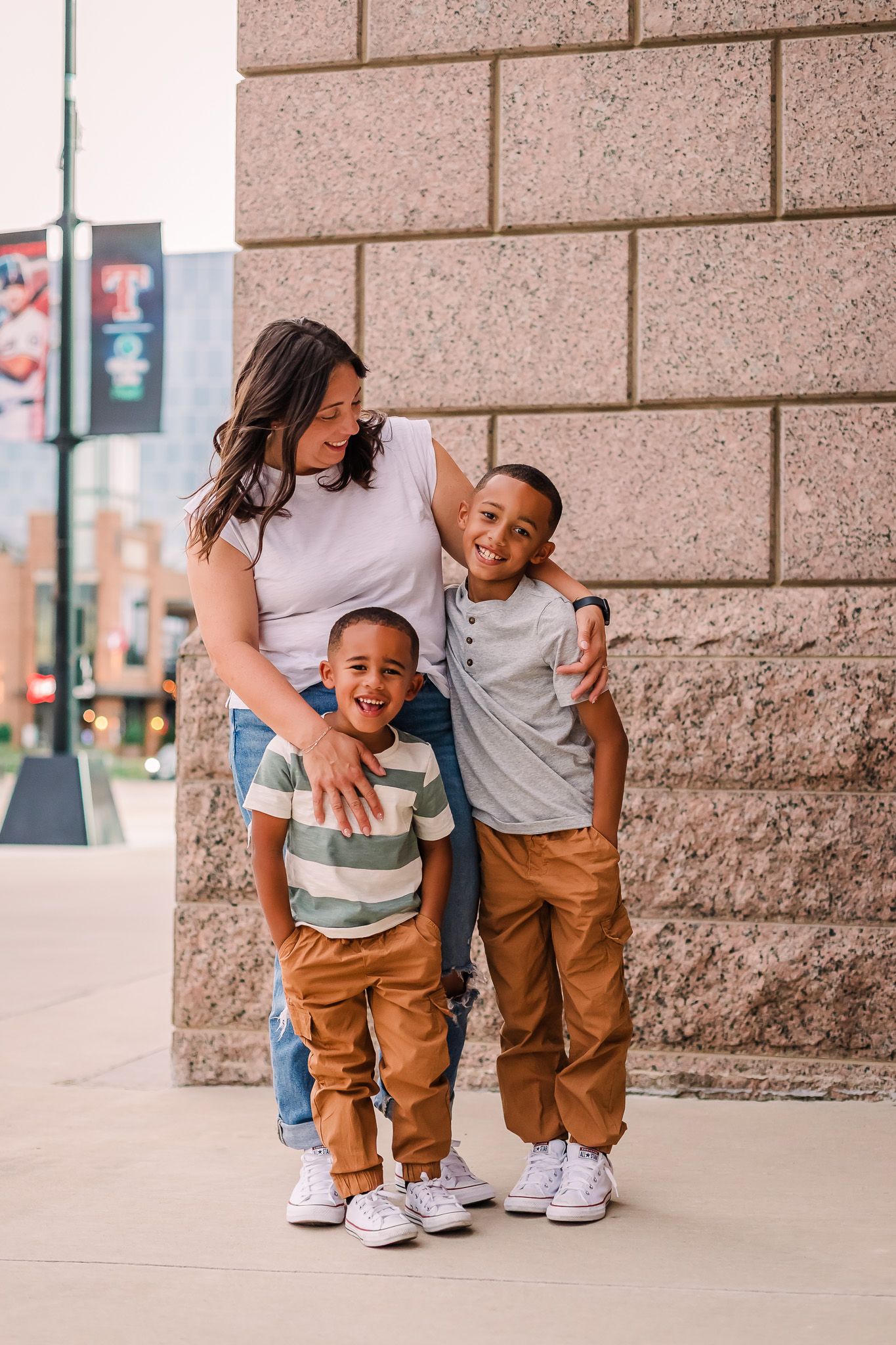 A family wearing coordinated outfits in brown and white poses together against a textured stone wall.