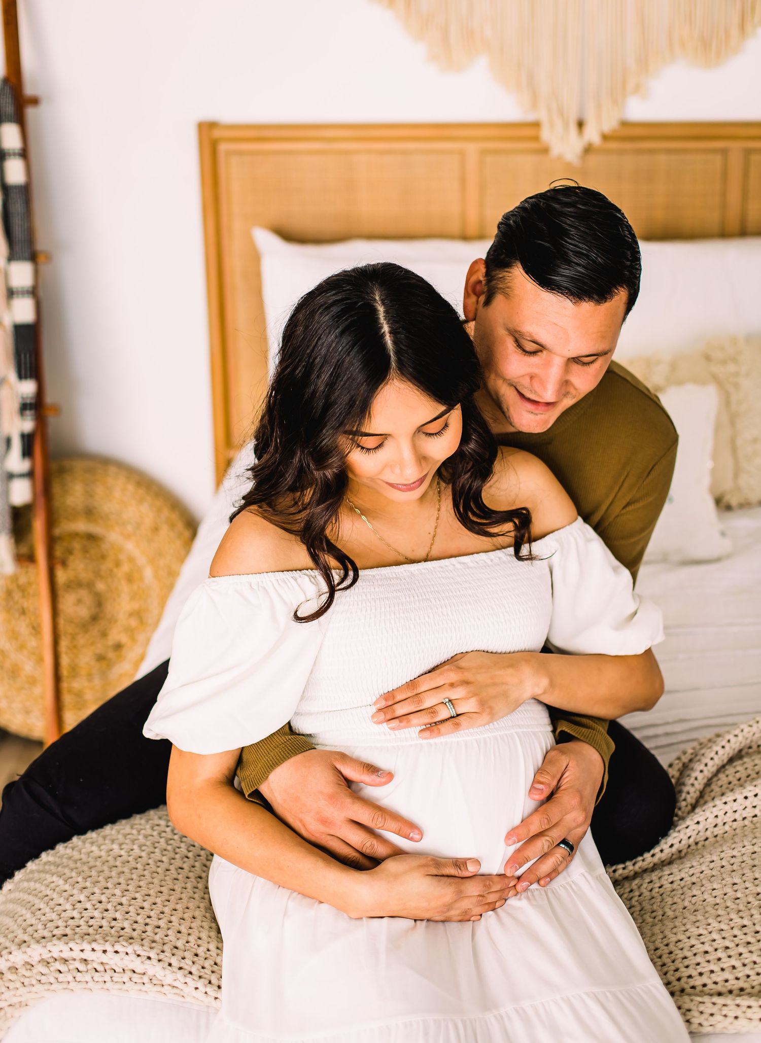 couple looking at pregnant belly on bed