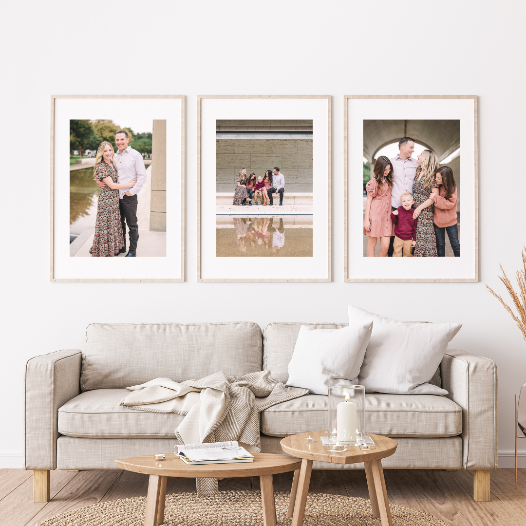 Modern living room interior with beige sofa, wooden coffee tables, and framed artwork displayed on white walls.