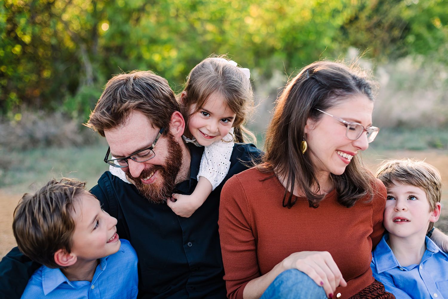 Close-up candid portrait of a family sharing genuine laughter and smiles together outdoors.
