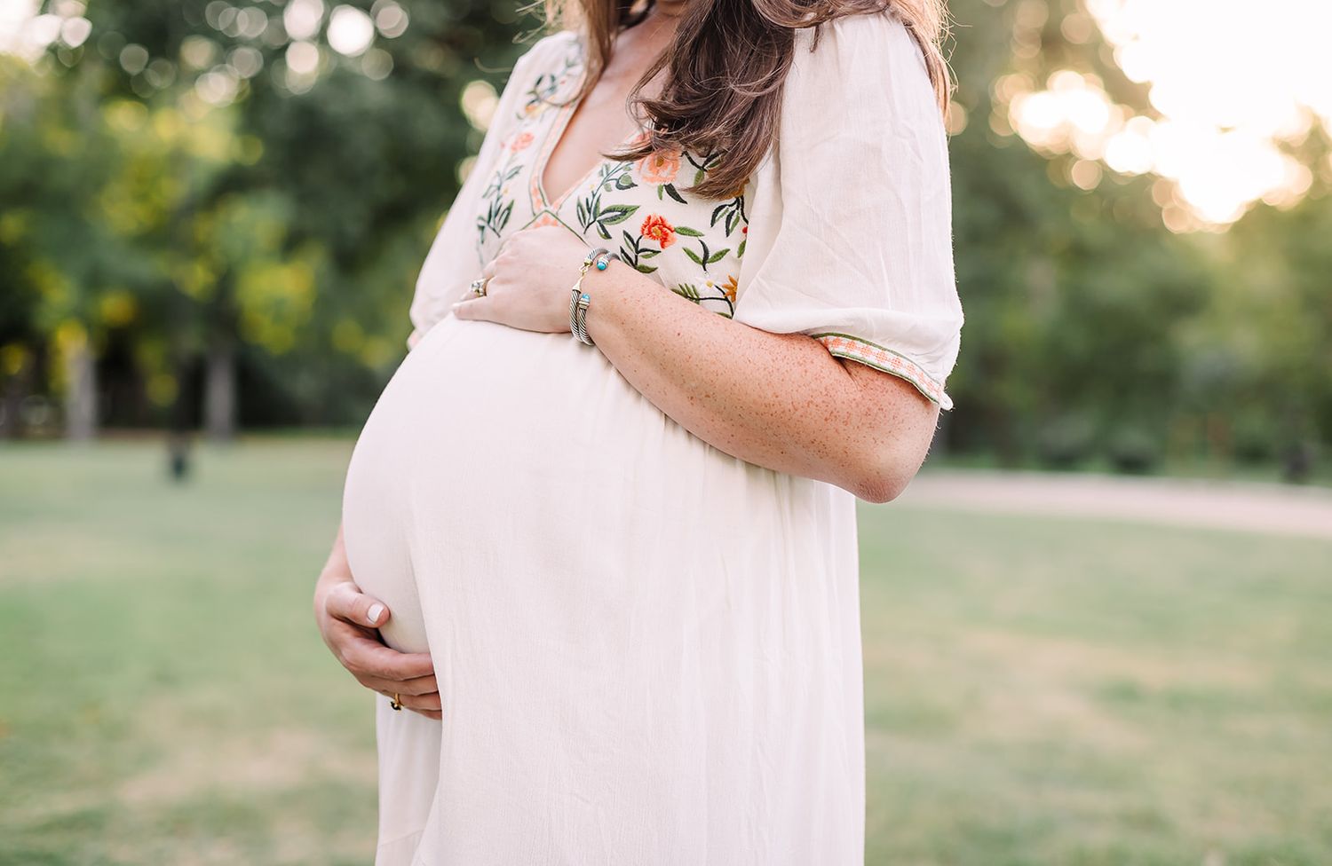 A series of maternity photos showing a pregnant woman in a white dress standing in a sunlit outdoor setting at Trinity Park Fort Worth TX