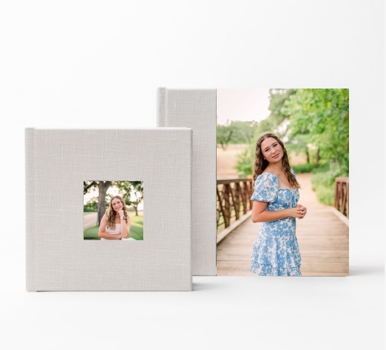A photo album with a square cutout window displaying a print photo next to a larger print on a white background.