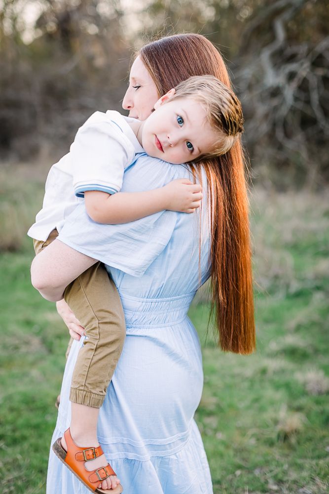 A tender moment captured in nature as two people share a warm embrace against a soft blurred outdoor background in Fort Worth TX.