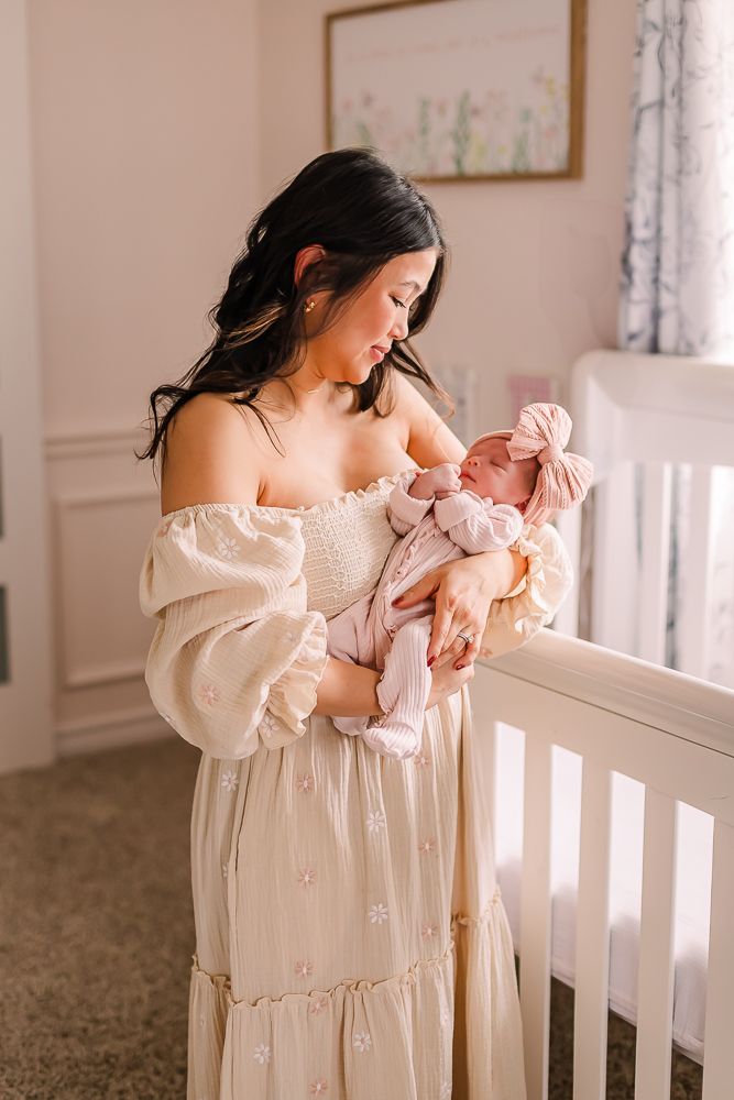 A tender moment captured in a sunlit nursery with soft white and pink tones creating a dreamy atmosphere mansfield newborn photos