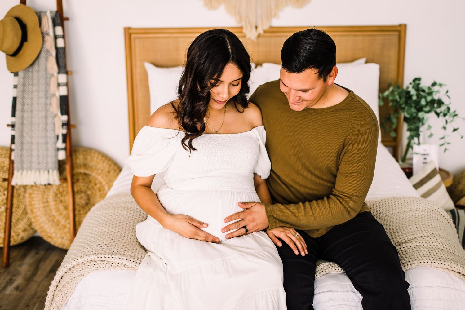 couple looking at pregnant belly on bed