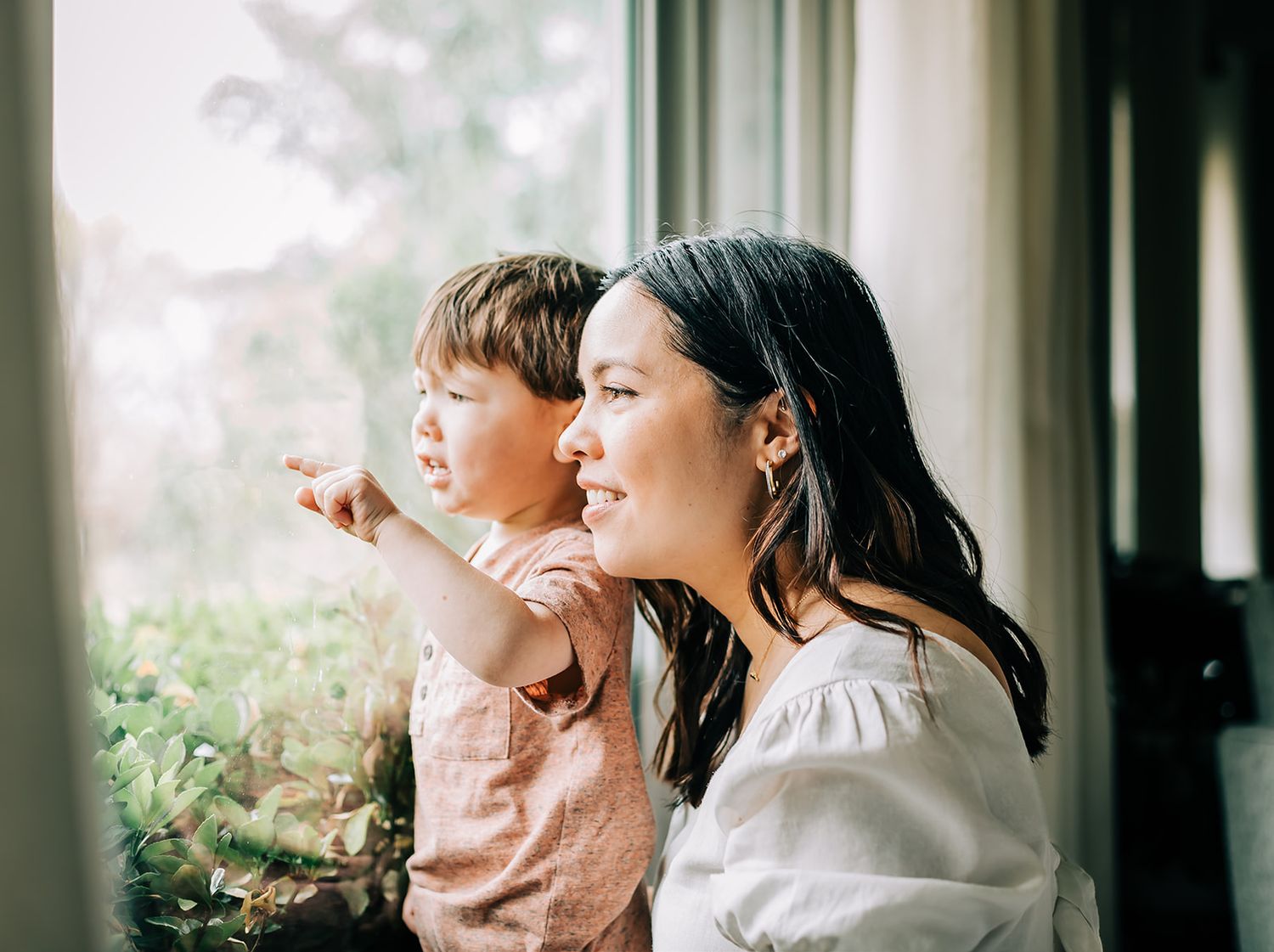 A family in coordinated outfits poses together against a bright window backdrop.