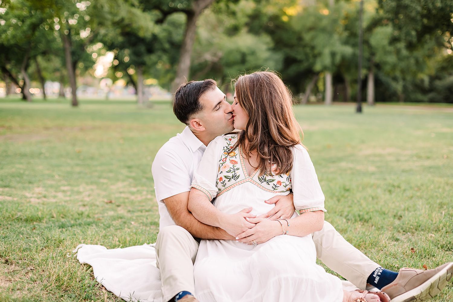 Intimate couple portraits taken outdoors with natural sunlight filtering through trees.