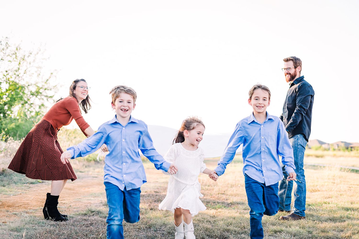 Family playing and running together in a field during golden hour.