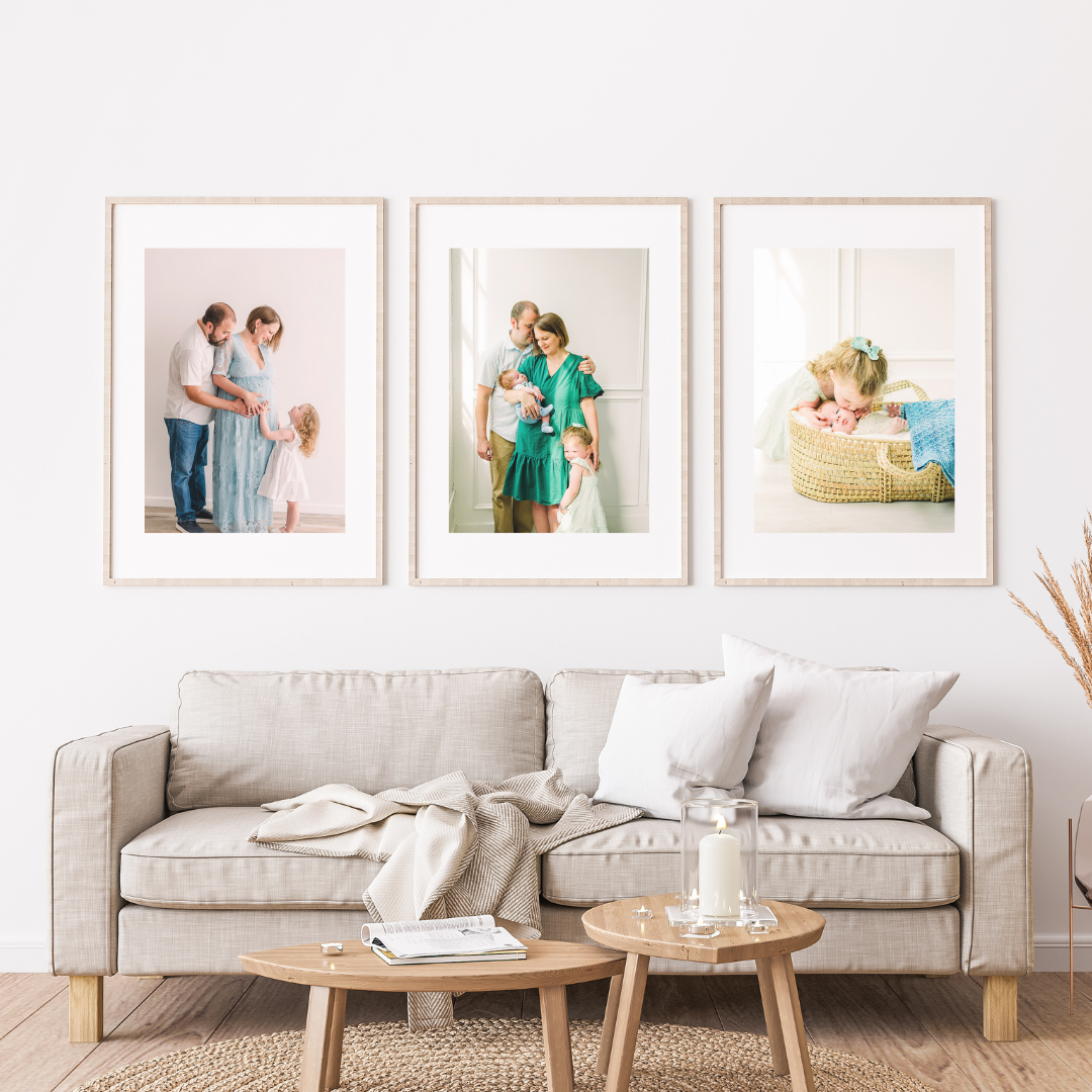 Modern living room interior with light gray sofa, wooden coffee tables and framed artwork on white walls.