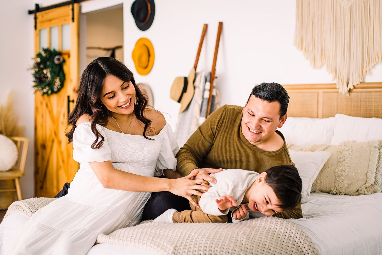 family laughing on bed maternity photoshoot