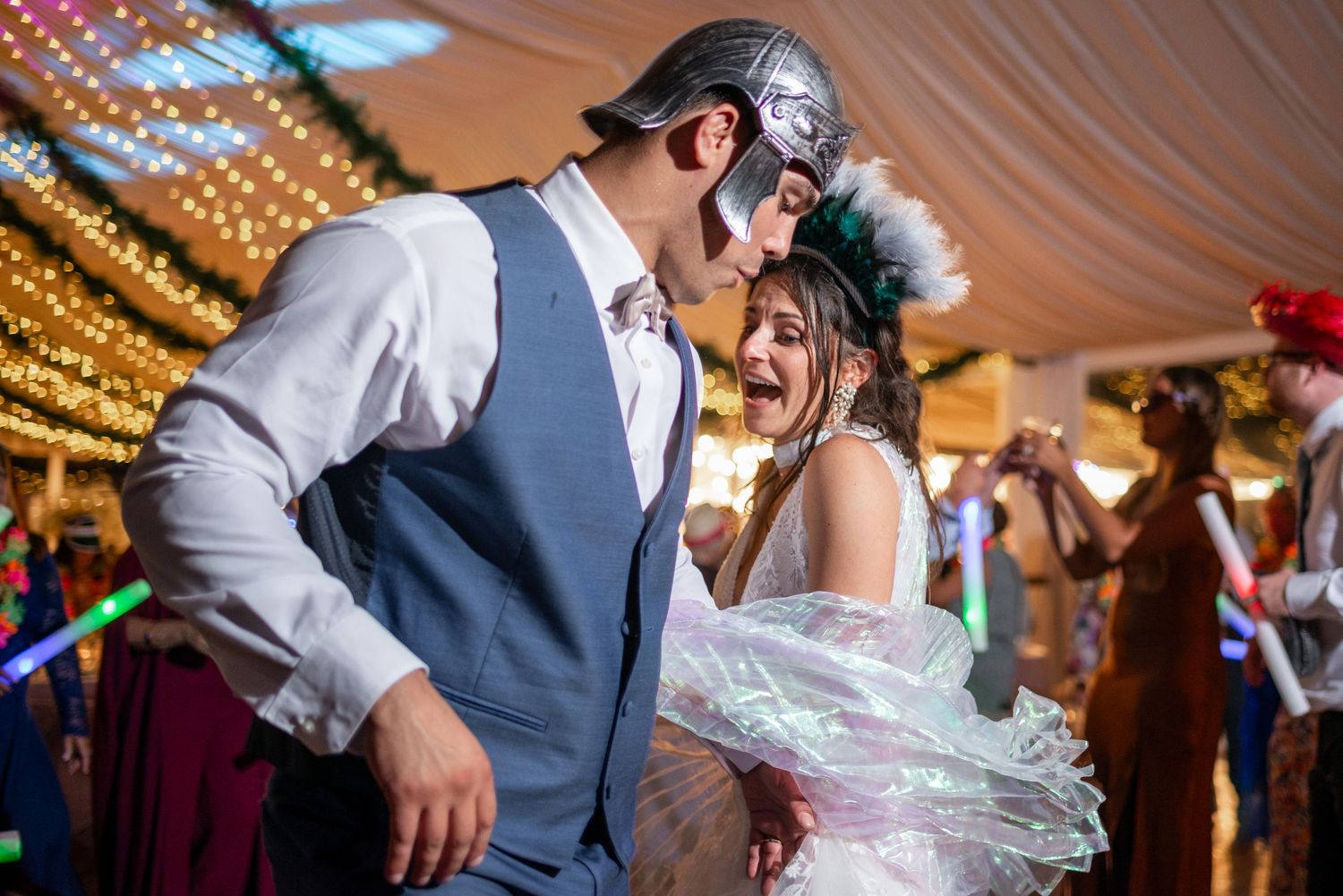 Wedding guests dancing and having fun under draped fabric ceiling with golden lighting effects.