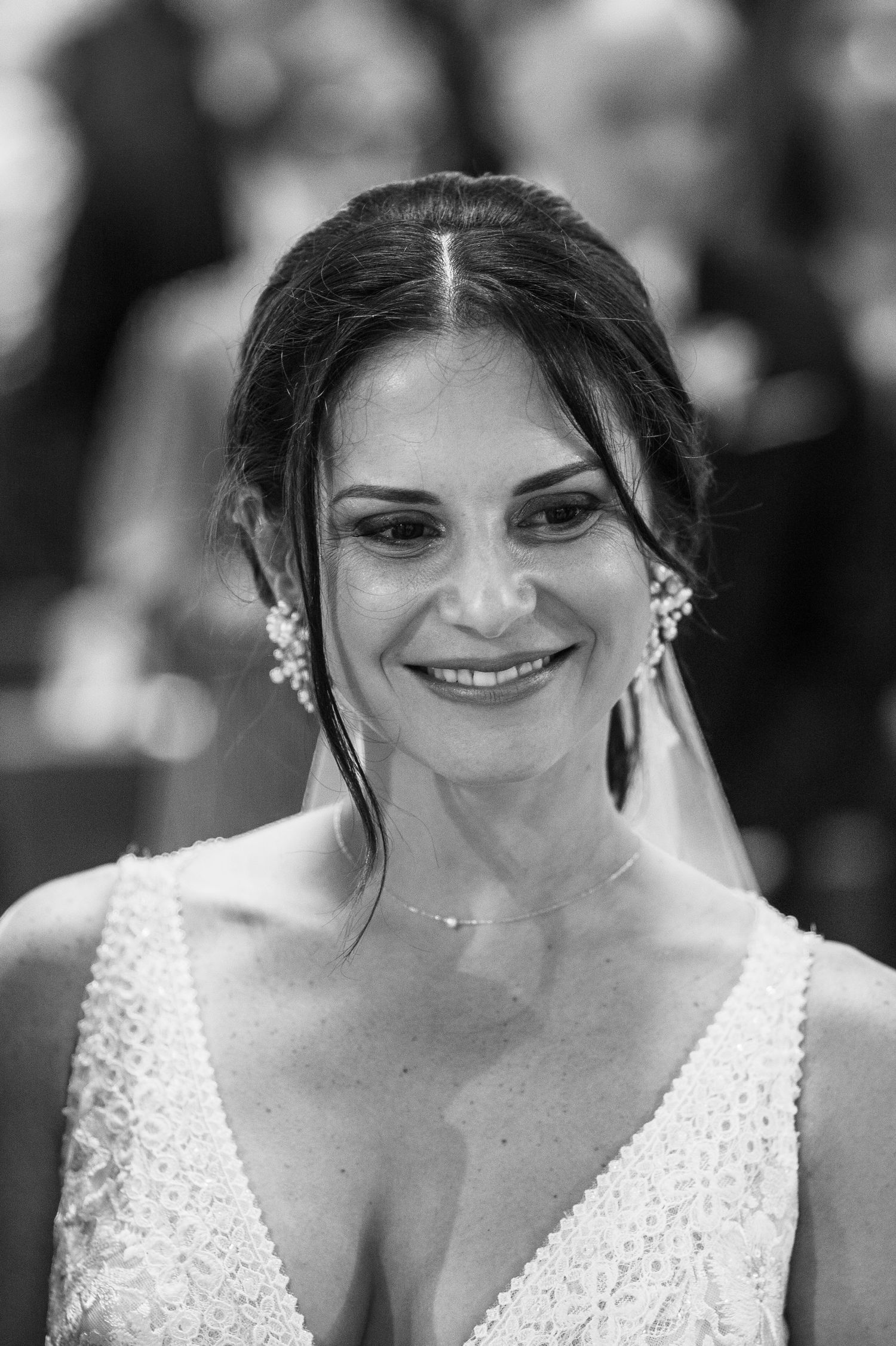 A bride in a white dress smiles warmly in a series of black and white portraits showing her joyful expression.