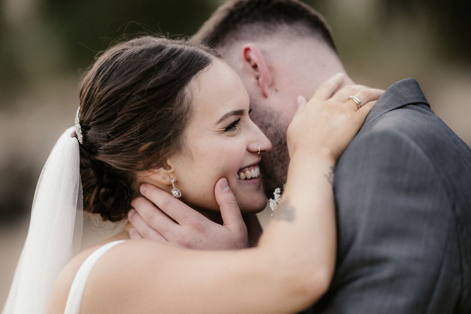 A romantic wedding moment captured in black and white as a couple shares a tender kiss outdoors.
