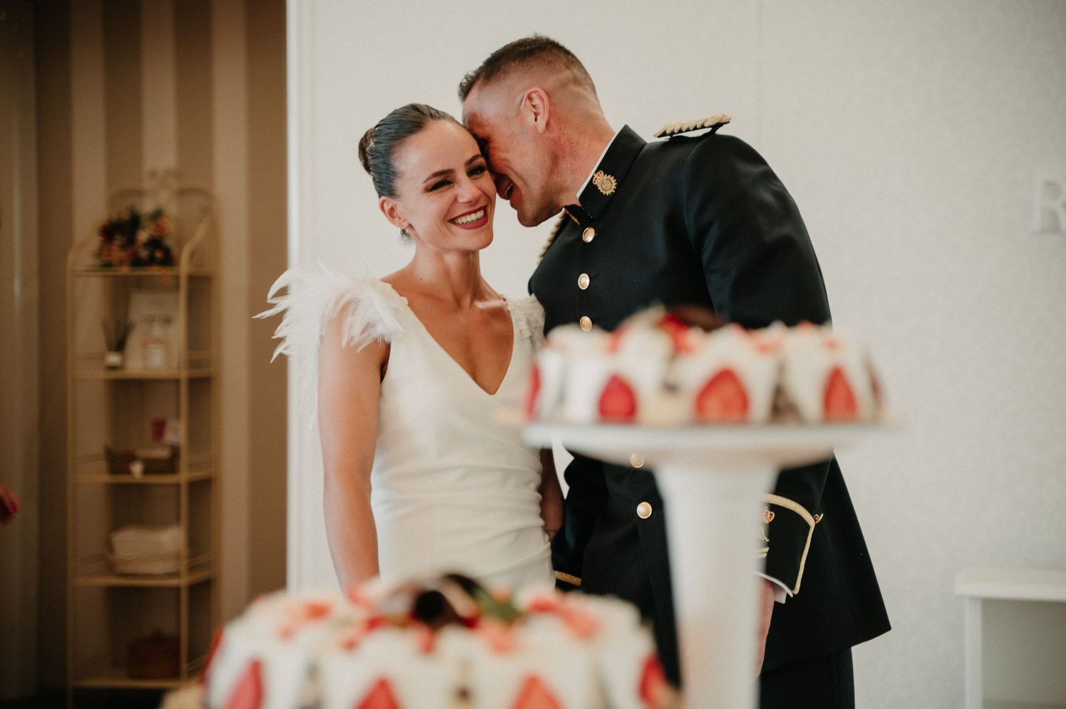A couple shares an intimate moment during their wedding ceremony in front of a white backdrop.