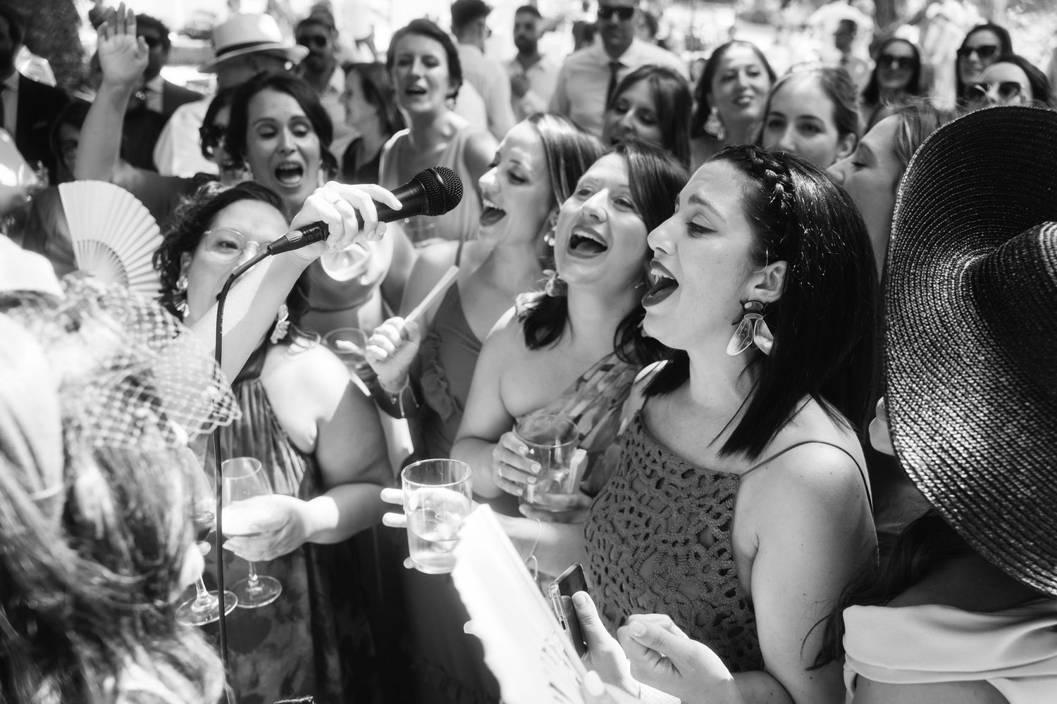 Wedding guests laugh together during an outdoor celebration with candid black and white photography.