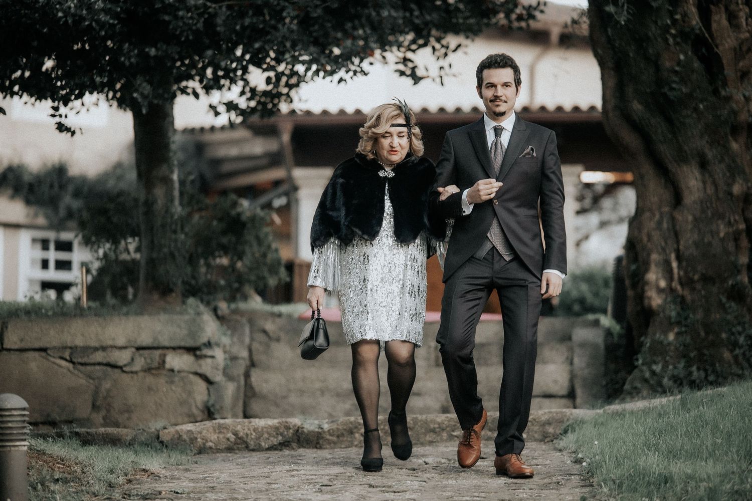 A couple walks together on a grassy path while holding hands during an outdoor photo session.