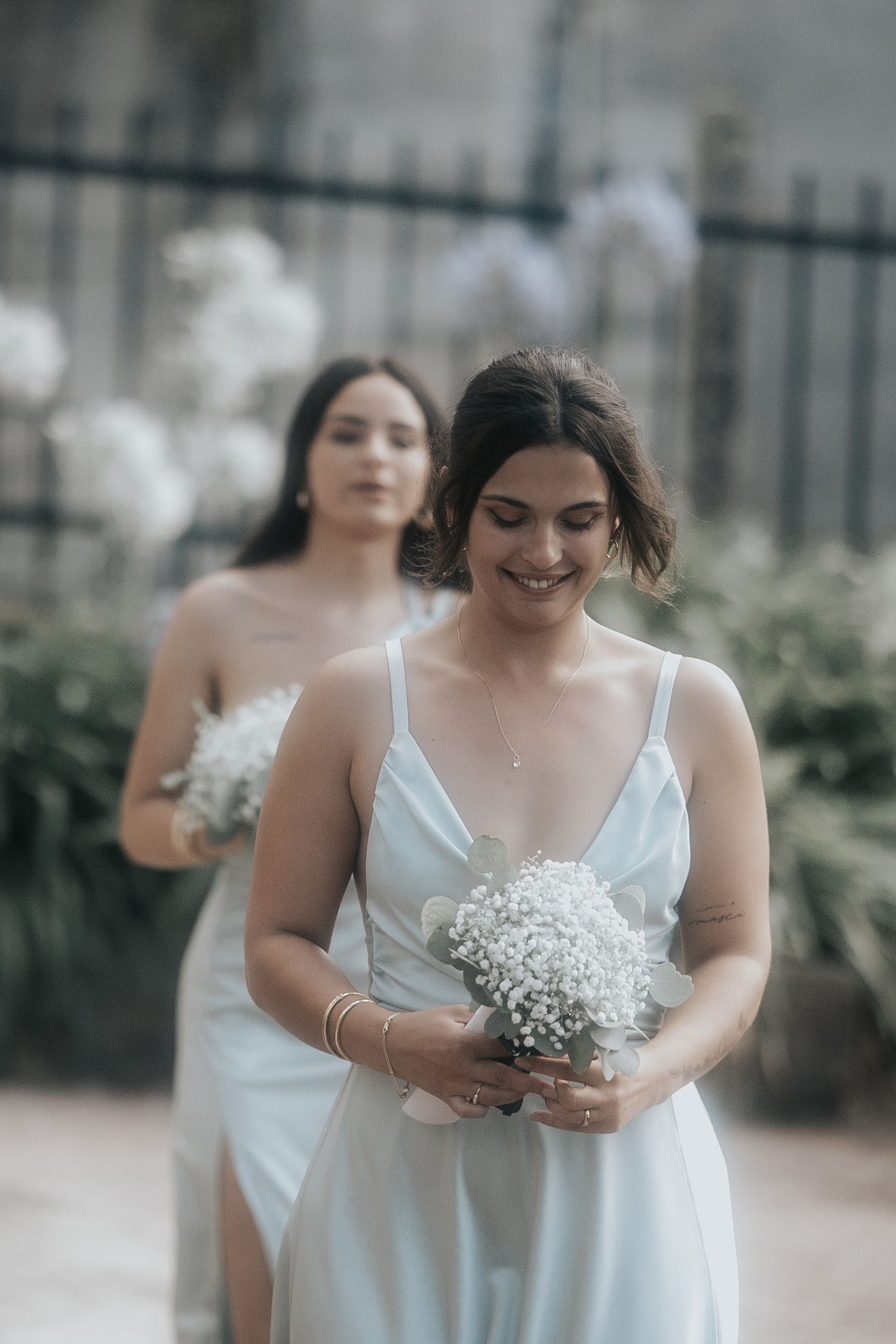 A person in a white dress holds a delicate bouquet of baby's breath flowers against a soft blurred background.