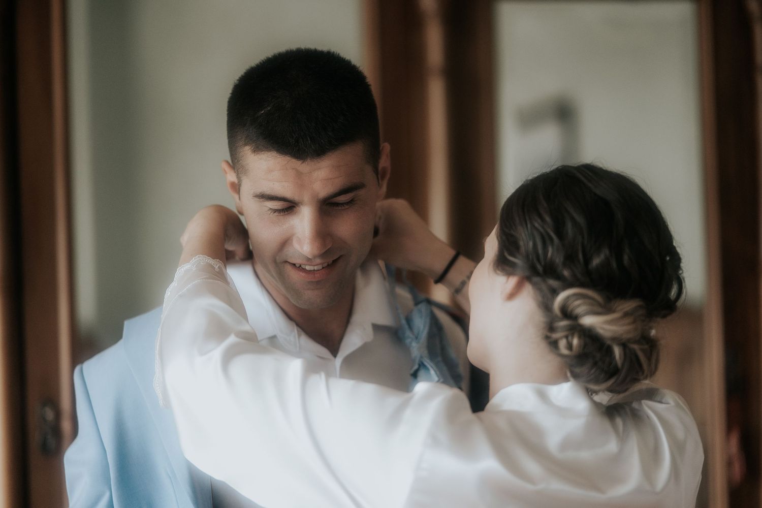 A couple shares an intimate moment while getting ready for their wedding day.