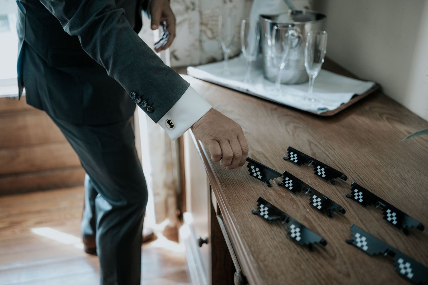 Person arranging domino pieces on a wooden table with glass jars in the background.
