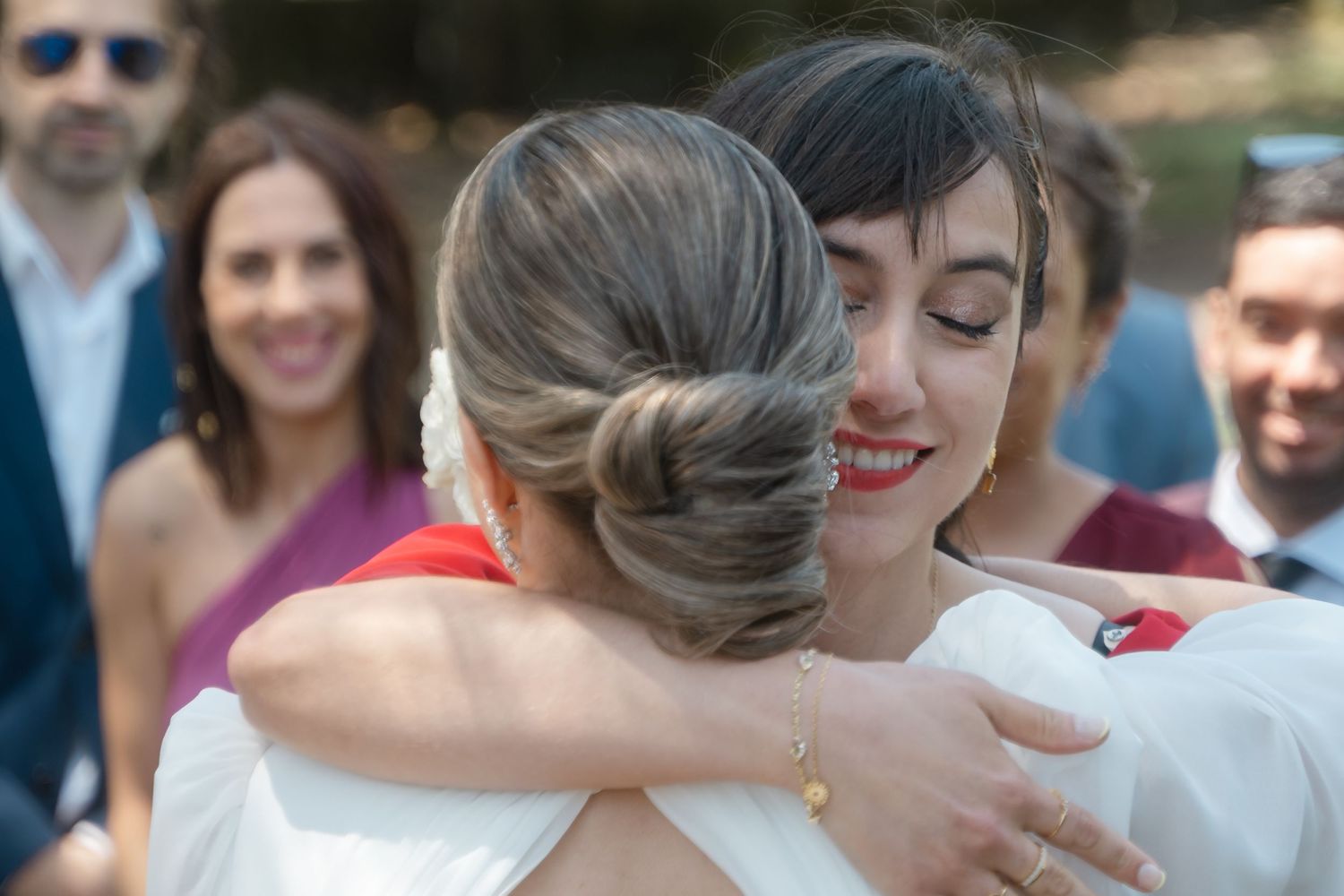 Wedding guests embrace and celebrate during an outdoor reception.