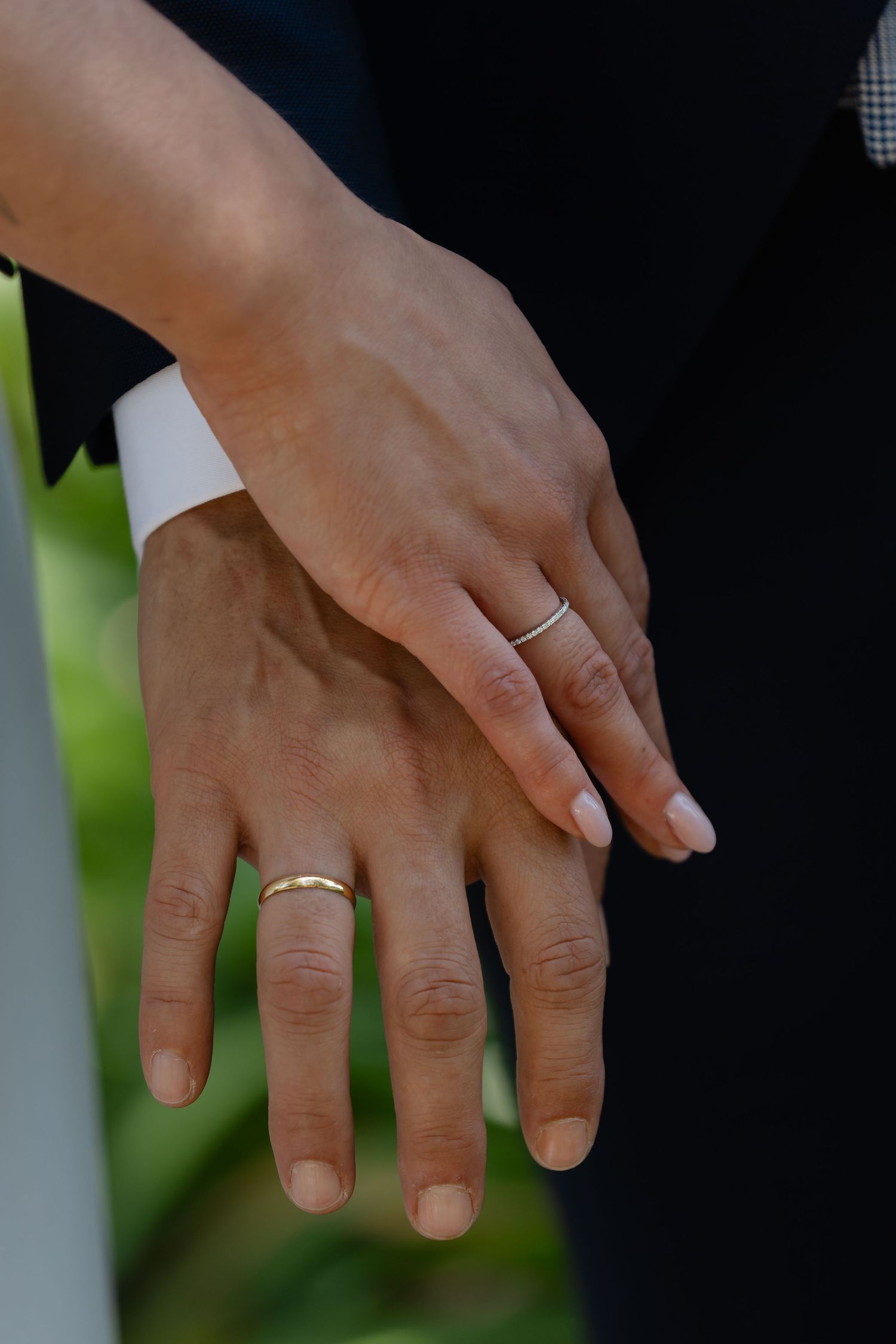 Close-up shot of hands displaying elegant wedding rings against a blurred background.