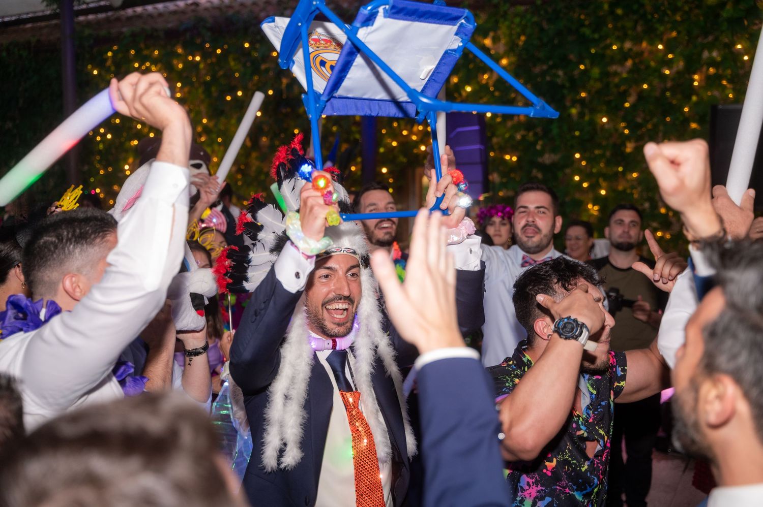 Wedding reception dance floor filled with energetic guests celebrating under string lights.