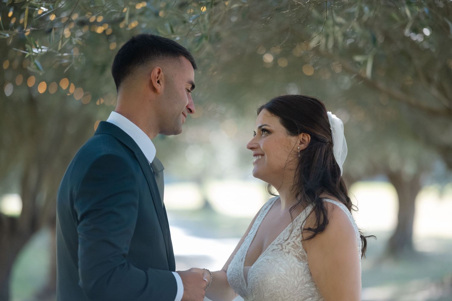 Romantic couple in wedding attire share intimate moments in a sun-dappled outdoor setting during their special day.