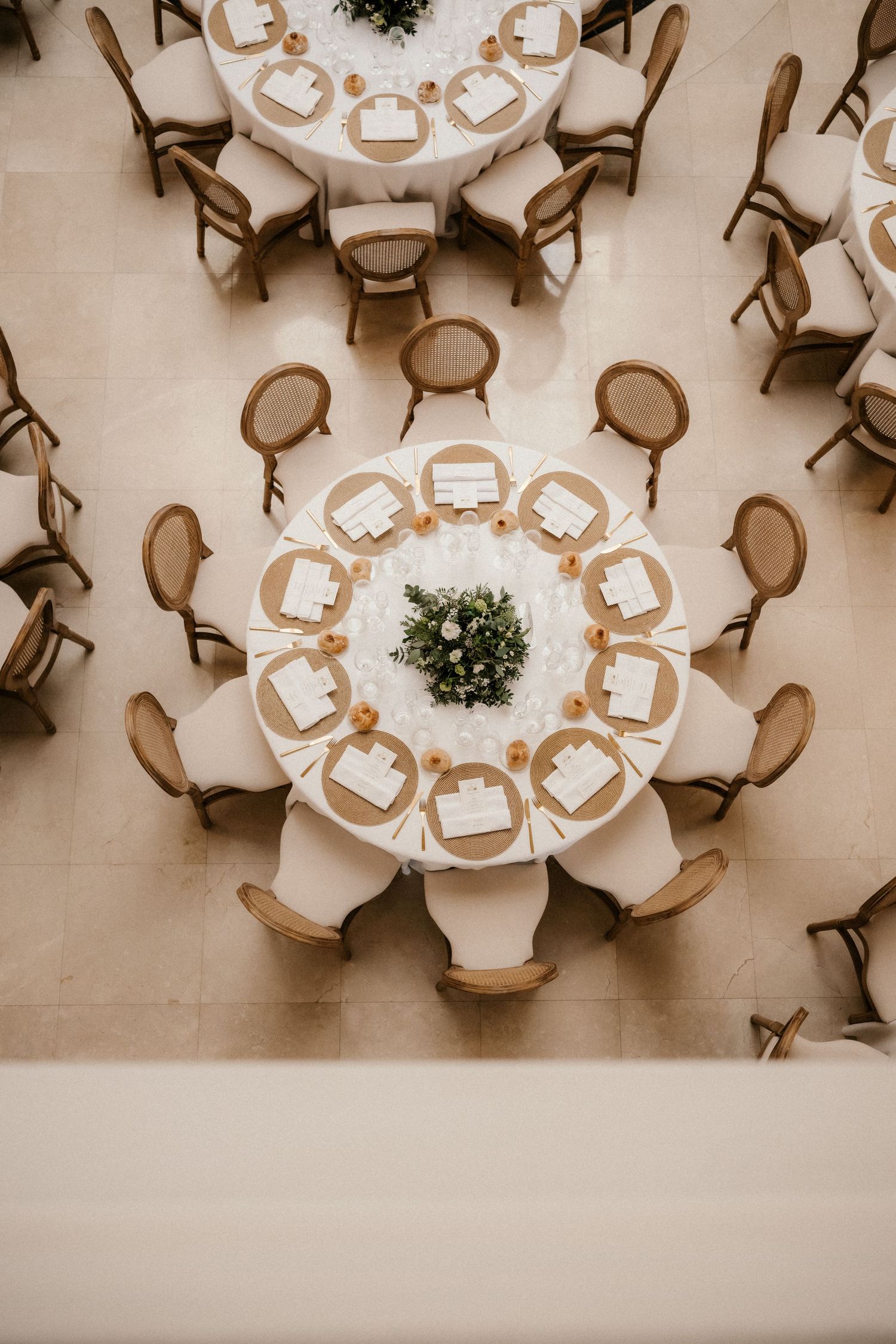 Aerial view of elegant round banquet tables with white tablecloths and chairs arranged in a circular pattern.